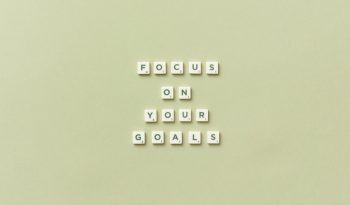 Scrabble letters forming a motivational phrase 'Focus on Your Goals' on a light green background.
