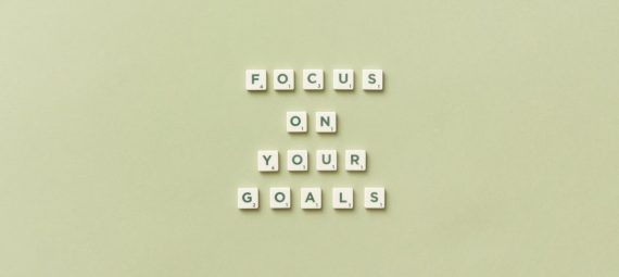 Scrabble letters forming a motivational phrase 'Focus on Your Goals' on a light green background.